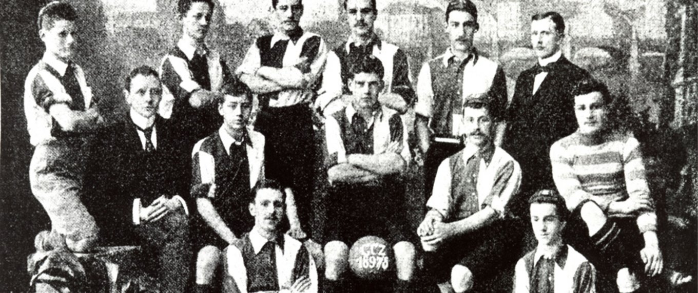 Originales Mannschaftsfoto des Grasshopper Club Zürich aus dem Jahr 1893 - vierzehn Spieler in Hemden und Westen rund um einen Lederball mit GCZ-1893-Beschriftung.